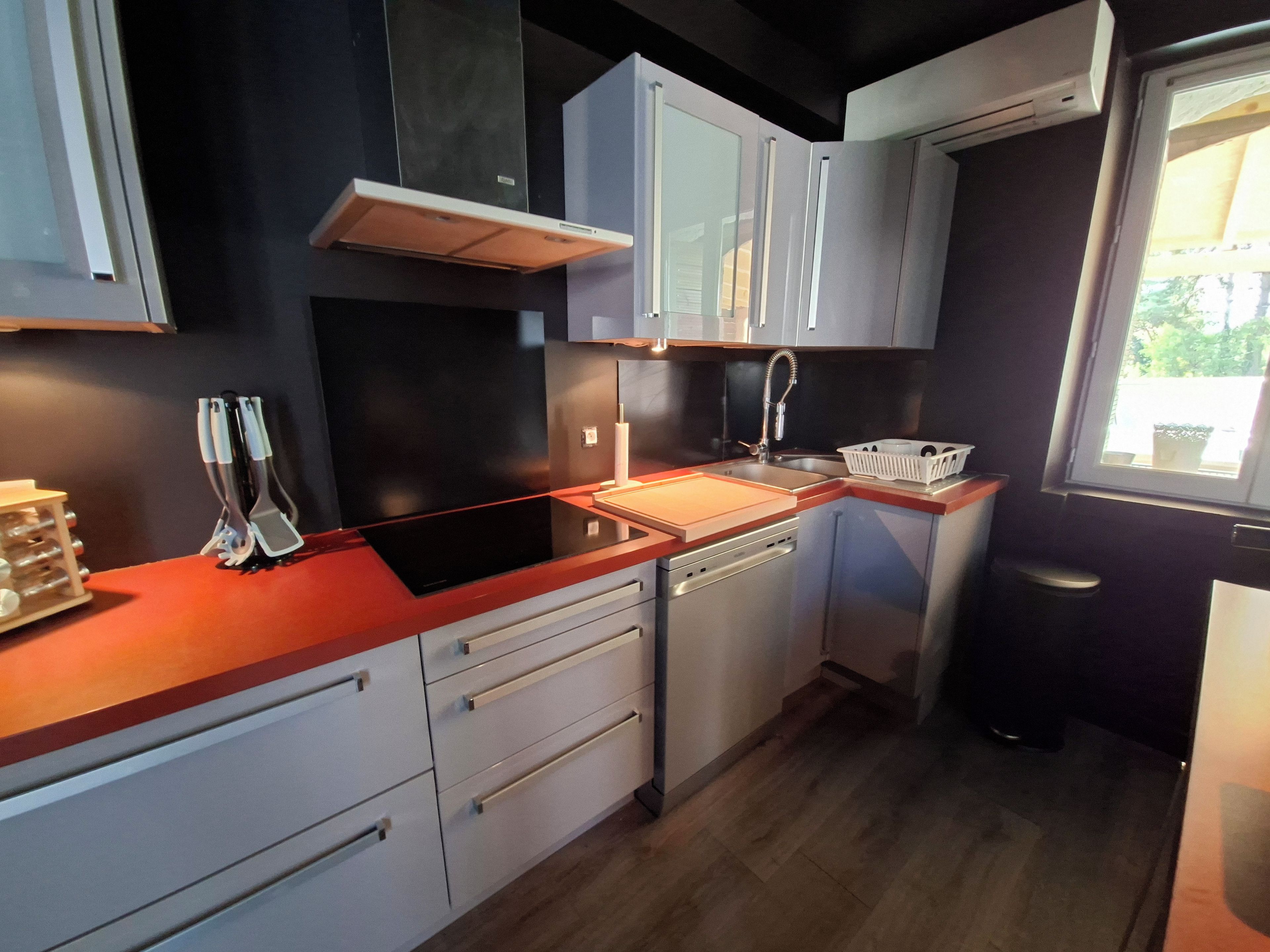 A modern kitchen with a built-in dishwasher, a stainless steel sink, and a window providing natural light.