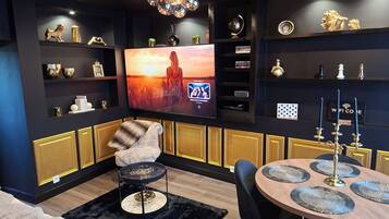 Una sala moderna con televisor de pantalla plana, un rincón de descanso acogedor y una lámpara decorativa.