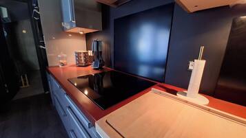 Una cocina moderna con tope de inducción negro, armarios de madera y horno empotrado.