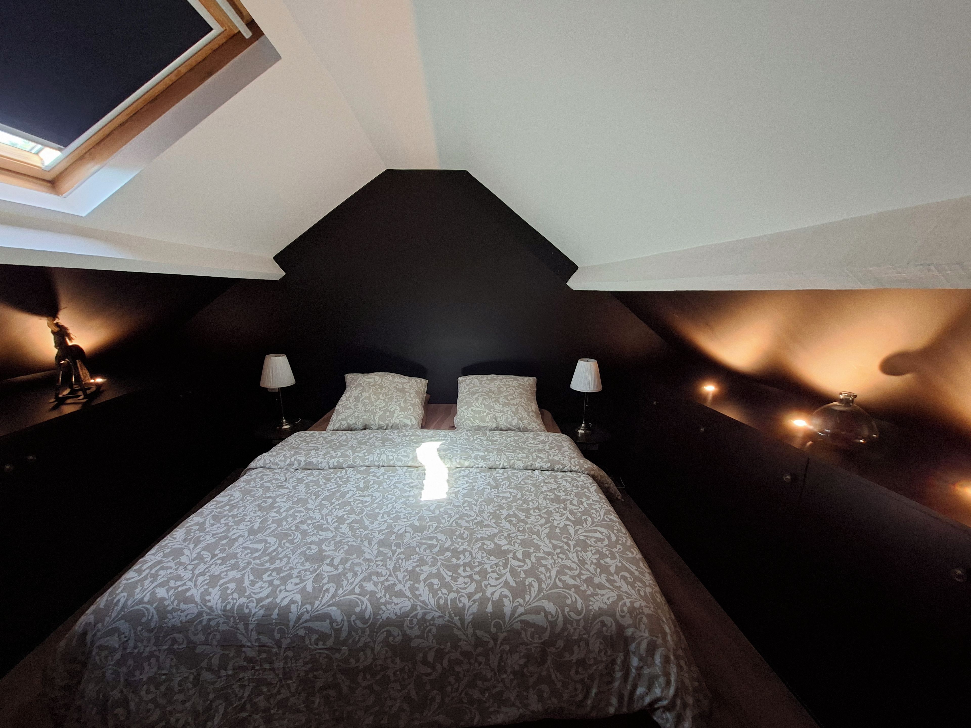 Une chambre à coucher avec un lit, deux tables de chevet, une lampe et une fenêtre.