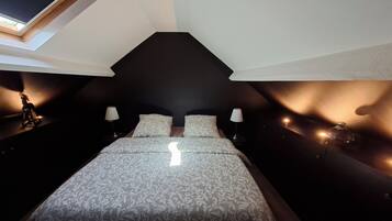 Une chambre à coucher avec un lit, deux tables de chevet, une lampe et une fenêtre.