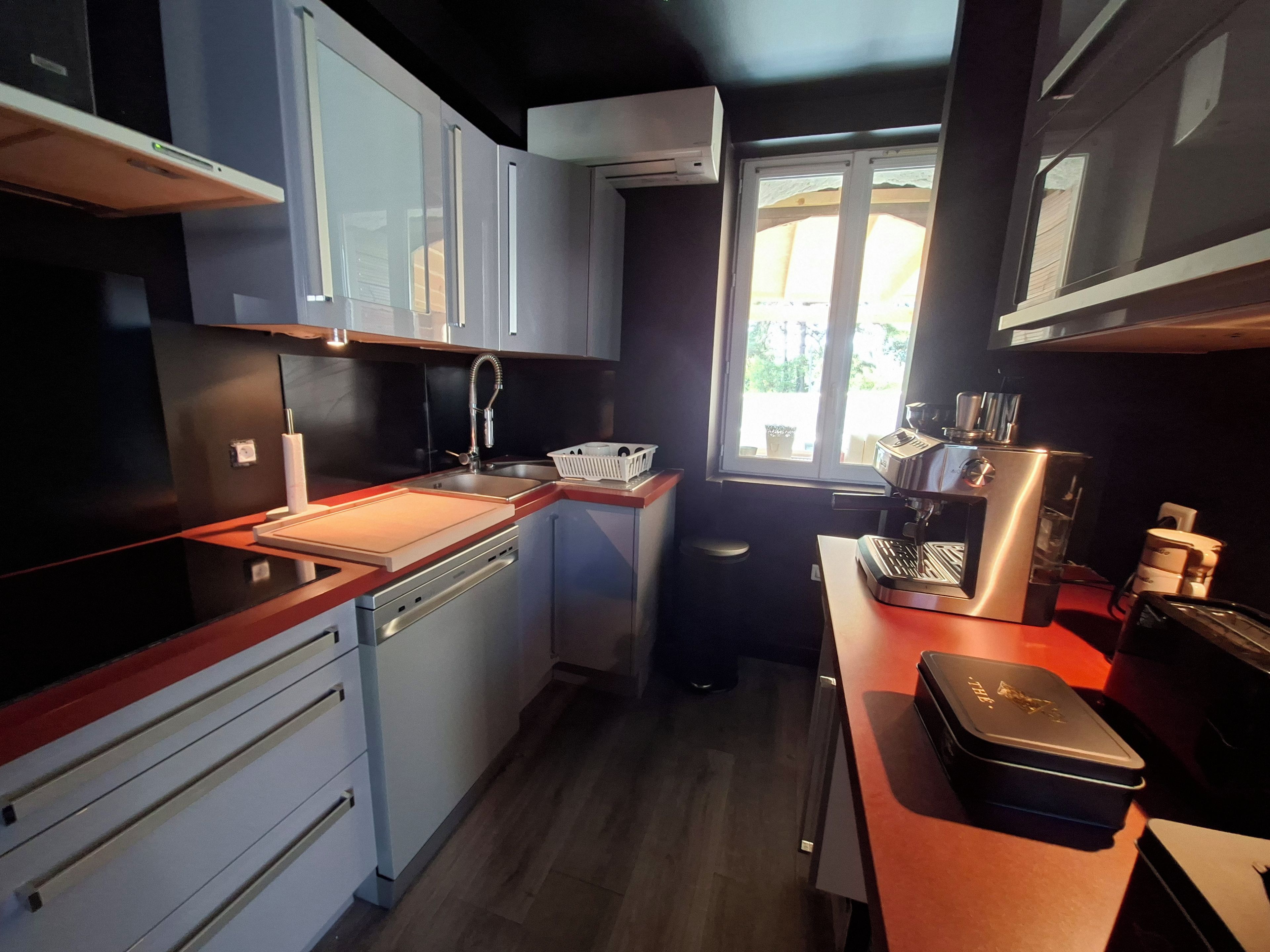 Cocina compacta con lavavajillas, un lavabo y una ventana que deja entrar luz natural.