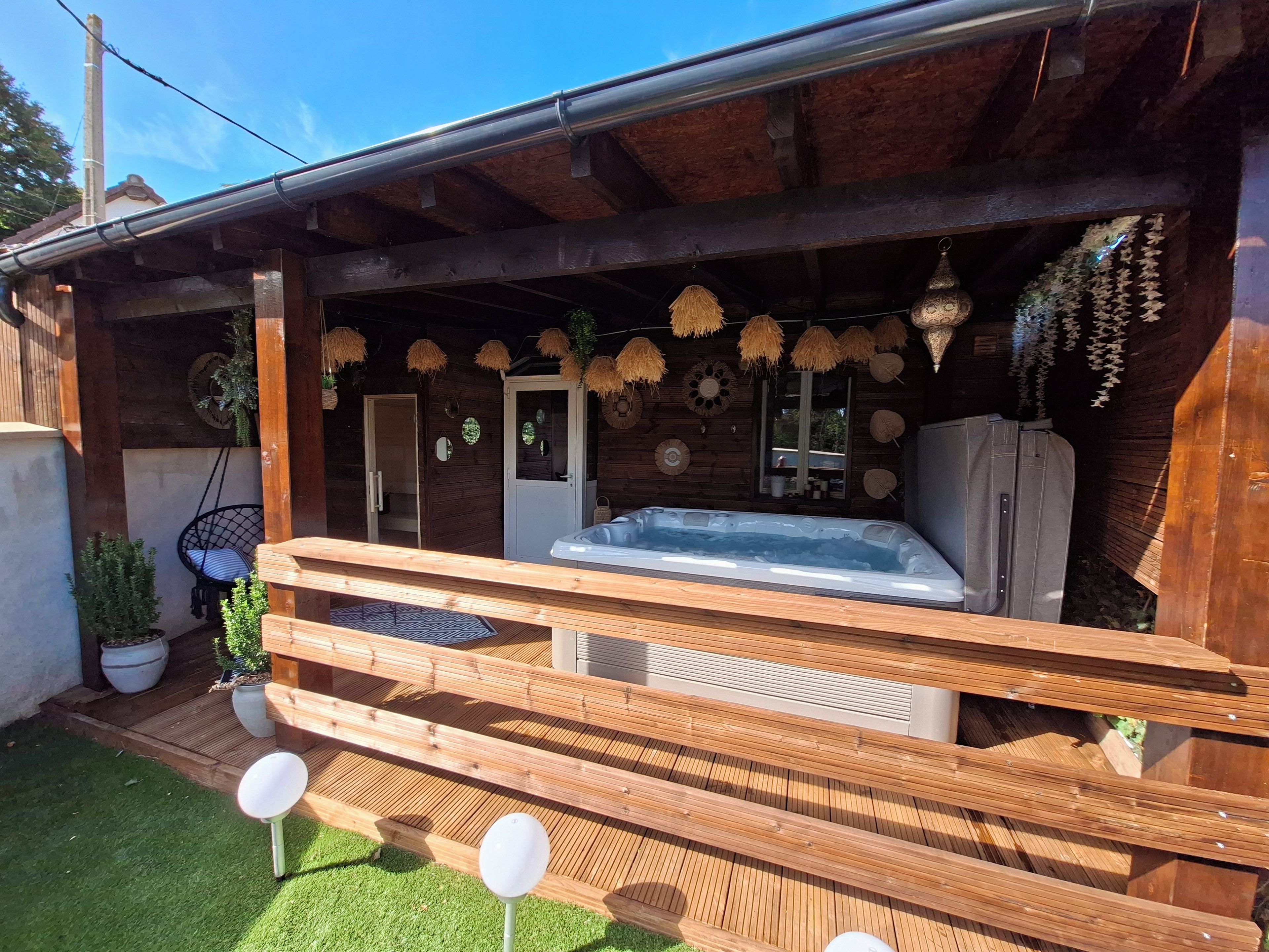 A wooden cabin with a hot tub, a wooden deck, and a garden area.