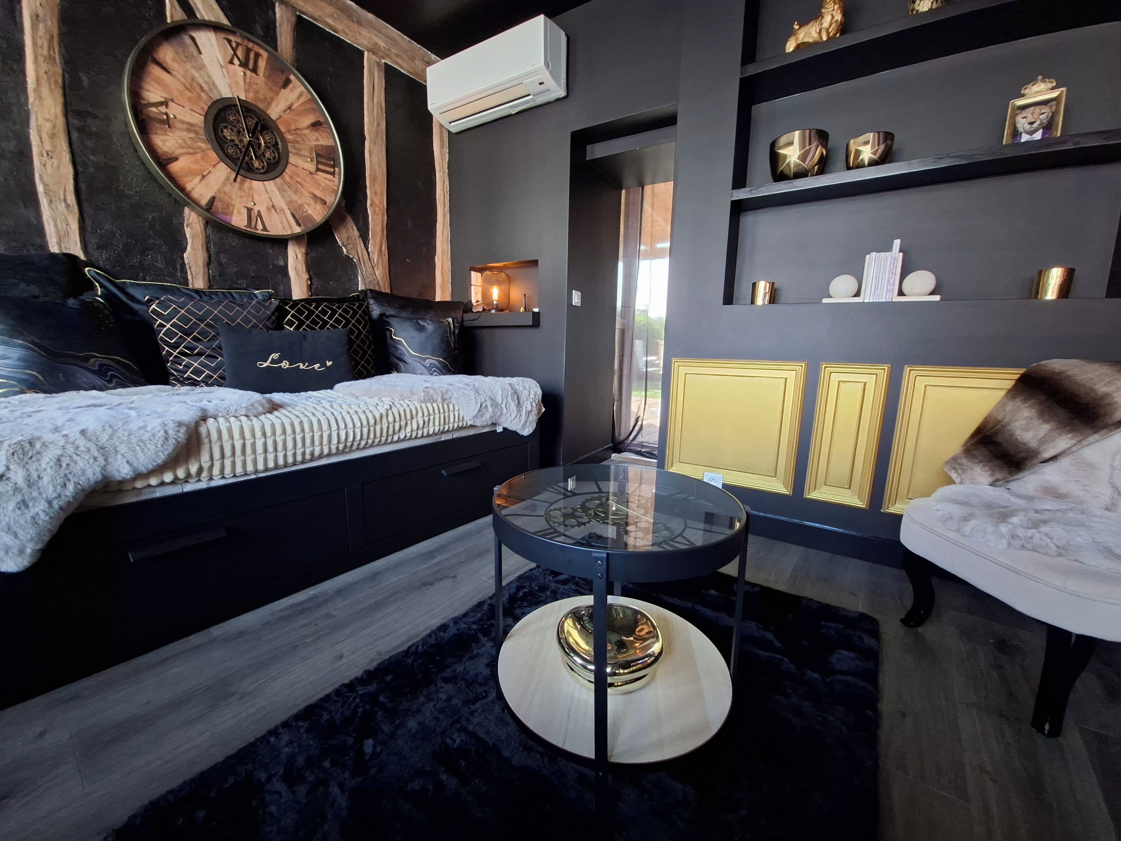 Ein modernes Wohnzimmer mit einer Couch, einem runden Couchtisch und dekorativen Gegenständen auf Regalen.