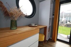 Una cocina moderna con encimera de madera, un espejo redondo y un florero con plantas secas.