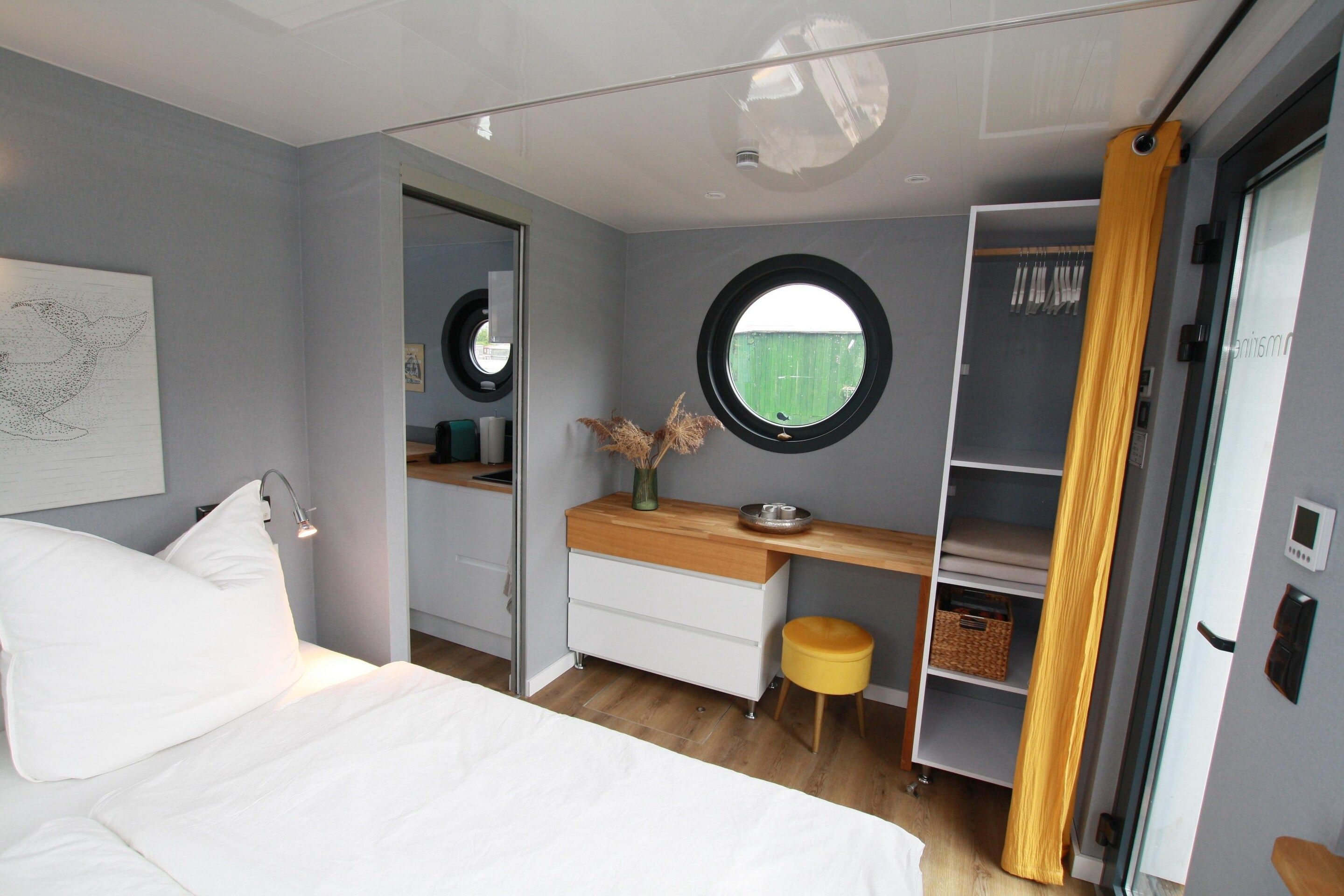 Ein Schlafzimmer mit einem Bett, einem Schreibtisch, einem Kleiderschrank und einem runden Spiegel.