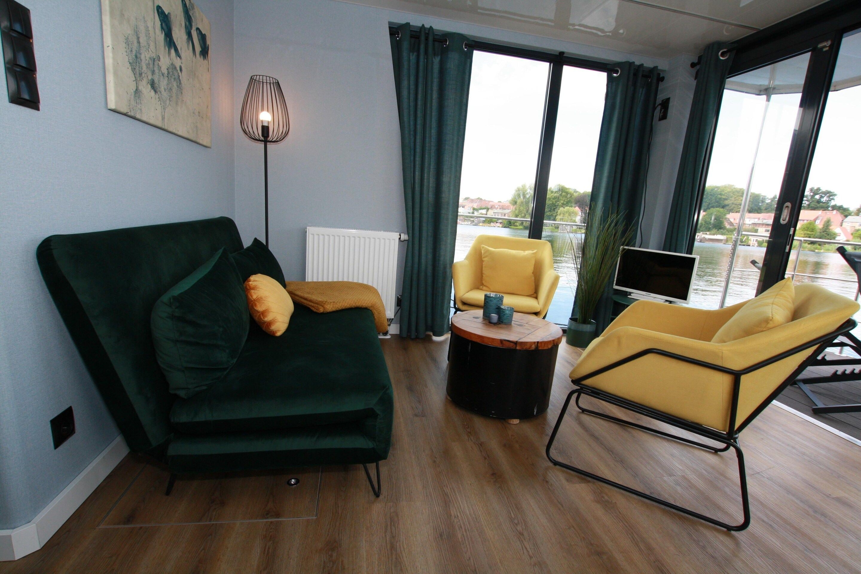 Ein modernes Wohnzimmer mit einem grünen Sofa, einem gelben Sessel und einem runden Couchtisch.