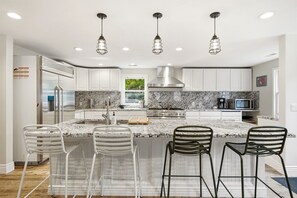A modern kitchen with white cabinetry, a marble countertop, and a stainless steel range hood. - Walk to Ski Trolley | Private Hot Tub | Sleeps 23 (Park City)