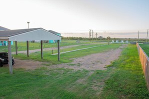 Ein Rasenstück mit einer überdachten Konstruktion, einem Fahrzeug und einem eingezäunten Bereich mit großen Lettern.