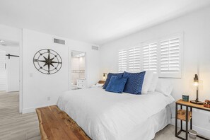 A bedroom with a large bed, a wooden bench, a wall clock, and a window with blinds. - Naples Bay Waterfront Dolphins, Boat Dock & Pool (Naples)