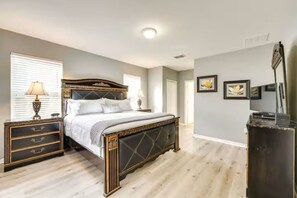 Een slaapkamer met een groot bed, nachtkastjes, een dressoir, een lamp en een flatscreen televisie.