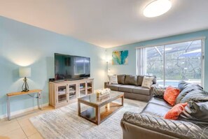 Ein Wohnzimmer mit Flachbildfernseher, einer Couch, einem Couchtisch und einem Fenster mit Blick.