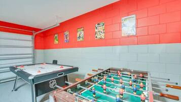 Una habitación con mesa de fútbol y mesa de billar, ambas con la marca de la NHL.