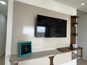 A reception area with a flat-screen TV mounted on the wall, a welcome sign, a wooden console table, and a small shelf with decorative items. - TOWER 694 BUILDING, APARTMENT 503 (Cartagena de Indias)