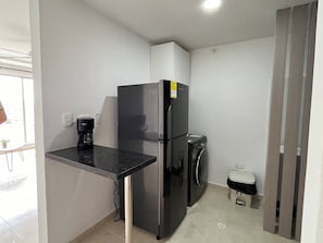 A compact kitchenette with a black refrigerator, a coffee maker, and a washing machine. - TOWER 694 BUILDING, APARTMENT 503 (Cartagena de Indias)