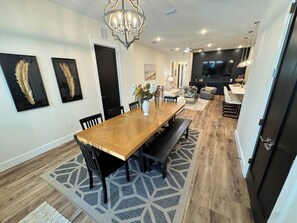 A modern dining area with a wooden table, black chairs, and a patterned rug. - Shell We Vacay 30A-Spacious 4 Bedroom - Private Saltwater Pool, PCB Florida (Panama City Beach)