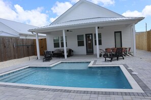 Ein Wohnhaus mit Schwimmbad, Außenbereich zum Sitzen und einer überdachten Terrasse.
