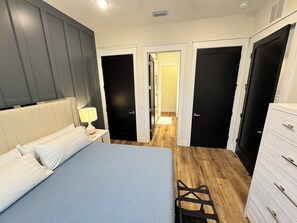 A bedroom with a bed, bedside table, lamp, and a dresser. - Shell We Vacay 30A-Spacious 4 Bedroom - Private Saltwater Pool, PCB Florida (Panama City Beach)