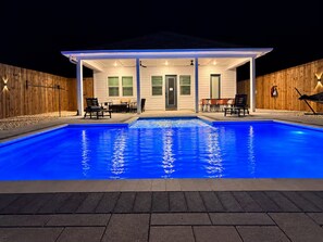 A swimming pool with a covered patio area, a door, and outdoor seating. - Shell We Vacay 30A-Spacious 4 Bedroom - Private Saltwater Pool, PCB Florida (Panama City Beach)