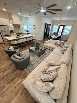 A modern living room with a large beige sectional sofa, a dark gray armchair, and a coffee table. - Shell We Vacay 30A-Spacious 4 Bedroom - Private Saltwater Pool, PCB Florida (Panama City Beach)