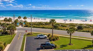Une vue sur la plage avec un espace de stationnement, des palmiers et un panneau de signalisation.