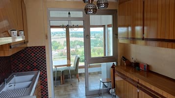 A kitchen with a sink, a dining area with a table and chairs, and a view through a glass door.