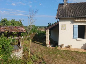 Ein rustikales Haus mit Ziegeldach, einem kleinen Garten und blauem Himmel.