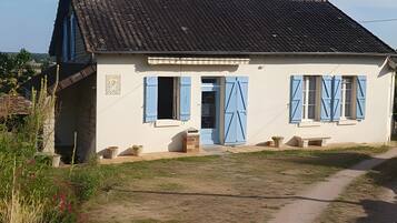 A two-story house with a sloped roof, a front door, and blue shutters.