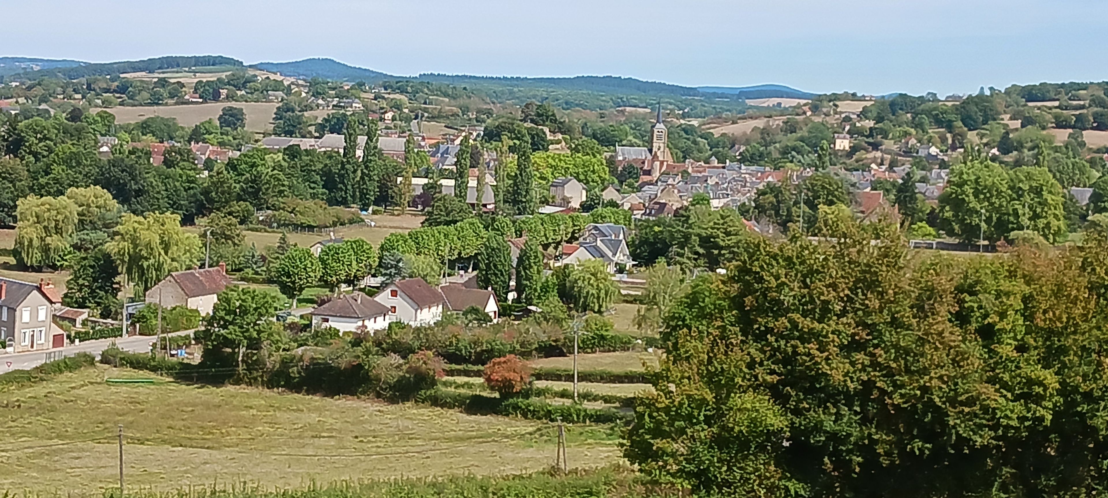 A rural landscape with a church, houses, and fields.