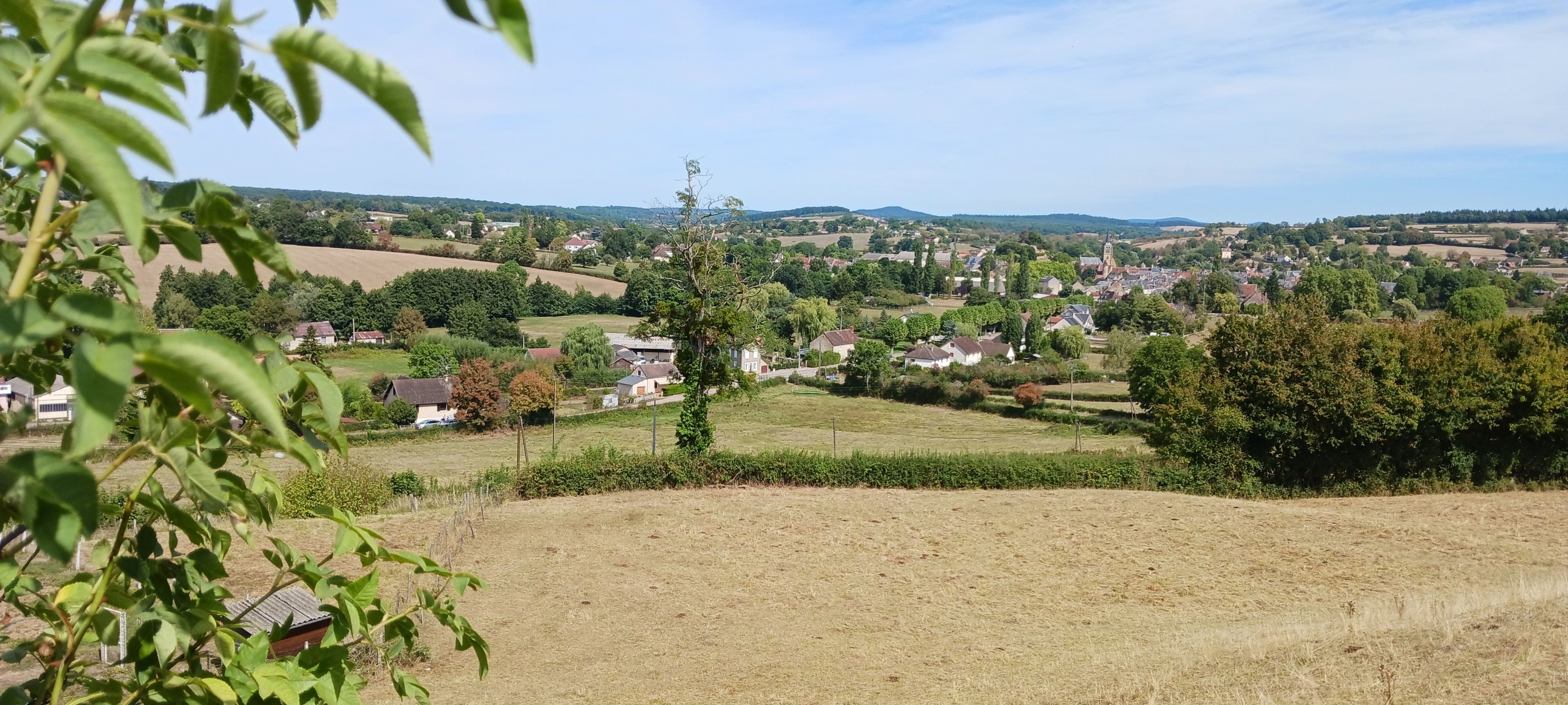 A rural landscape with houses, fields, and a church steeple.