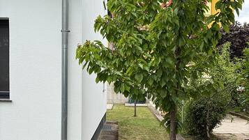 A building with a tiled roof, a tree in front, and a grassy area.