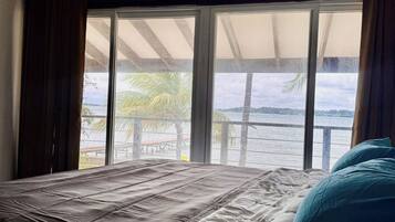 Una cama con vista a un balcón y al agua.