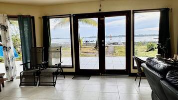 Amplia sala de estar con un gran ventanal corredero que da a un patio con vista a una masa de agua.