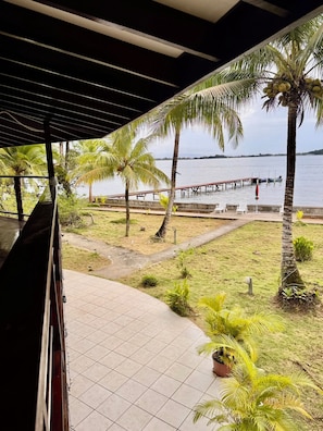 A covered outdoor area with a view of a water body, palm trees, and a dock. - Casa Maria Beach & Boat Club (Bocas del Toro)