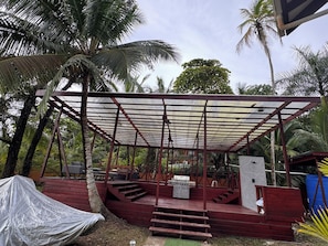 An outdoor covered area with a grill, seating, and steps leading up to it.