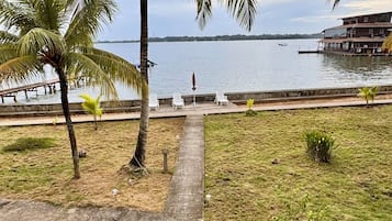 A waterfront property with a pathway leading to a seating area, palm trees, and a view of the water.