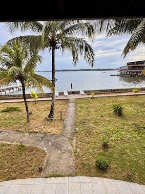 Una propiedad frente al agua con un camino que lleva a una zona de estar, palmeras y vista al agua.
