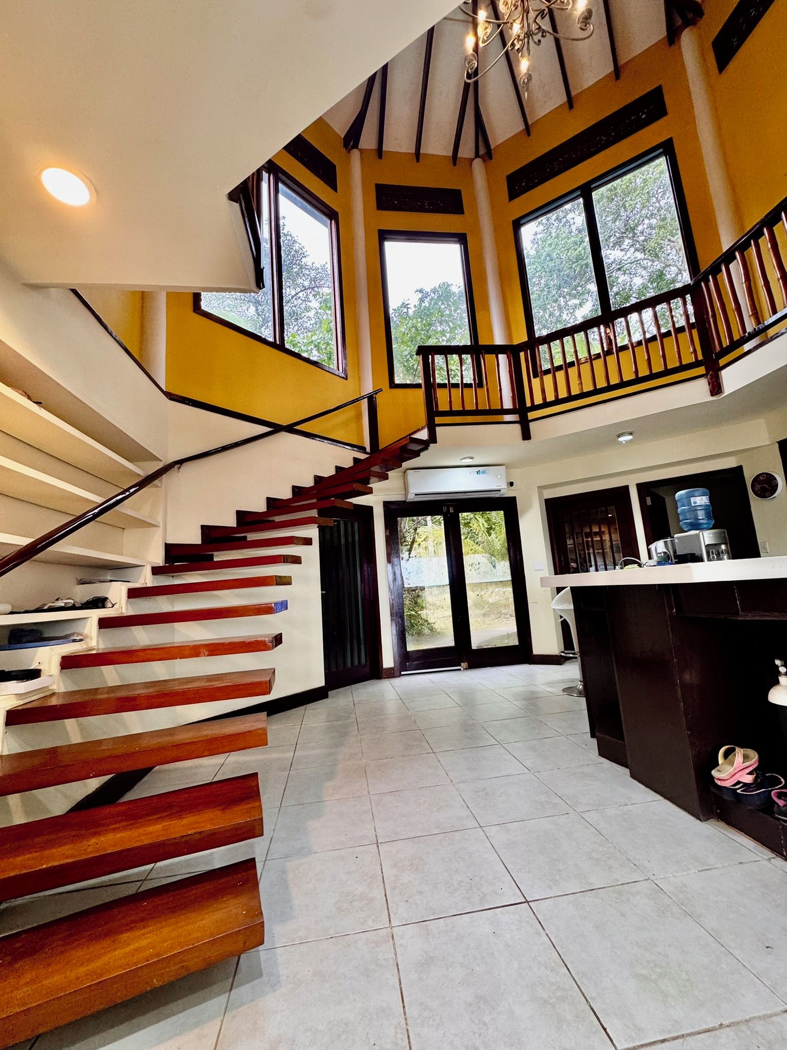 Un interior espacioso con una escalera central, ventanas amplias y una zona de cocina.