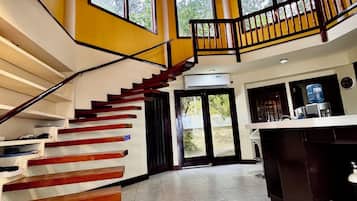 Un interior espacioso con una escalera central, ventanas amplias y una zona de cocina.