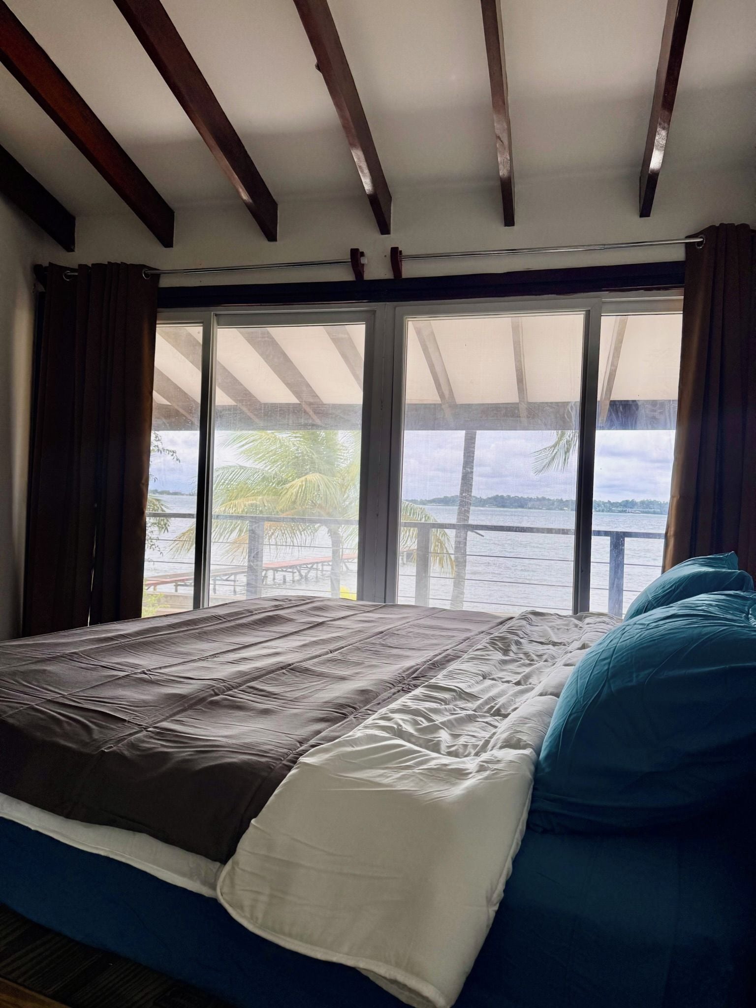 Una cama con vistas al mar a través de amplios ventanales.