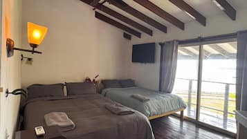 Una habitación con dos camas, ventilador de techo, televisor montado y ventana con cortinas.
