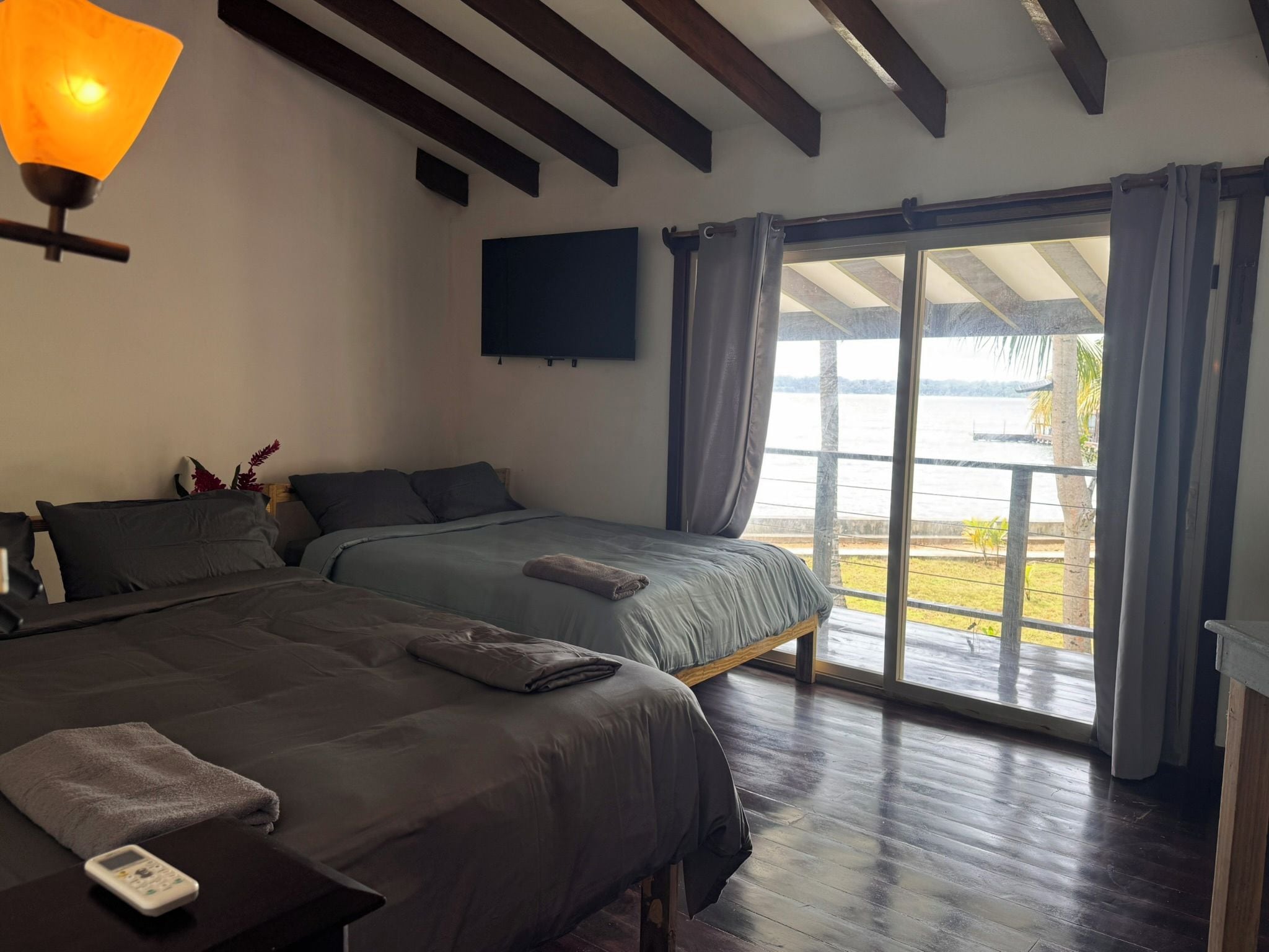 Una habitación de hotel con cama, una mesita de noche con lámpara, televisor y vistas al exterior.