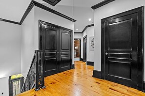 A hallway with wooden flooring, black doors, and a staircase with a metal railing. - Furnished Executive Townhome - Dedicated WFH Office - Ideal for 6+ Month Stays (Atlanta)