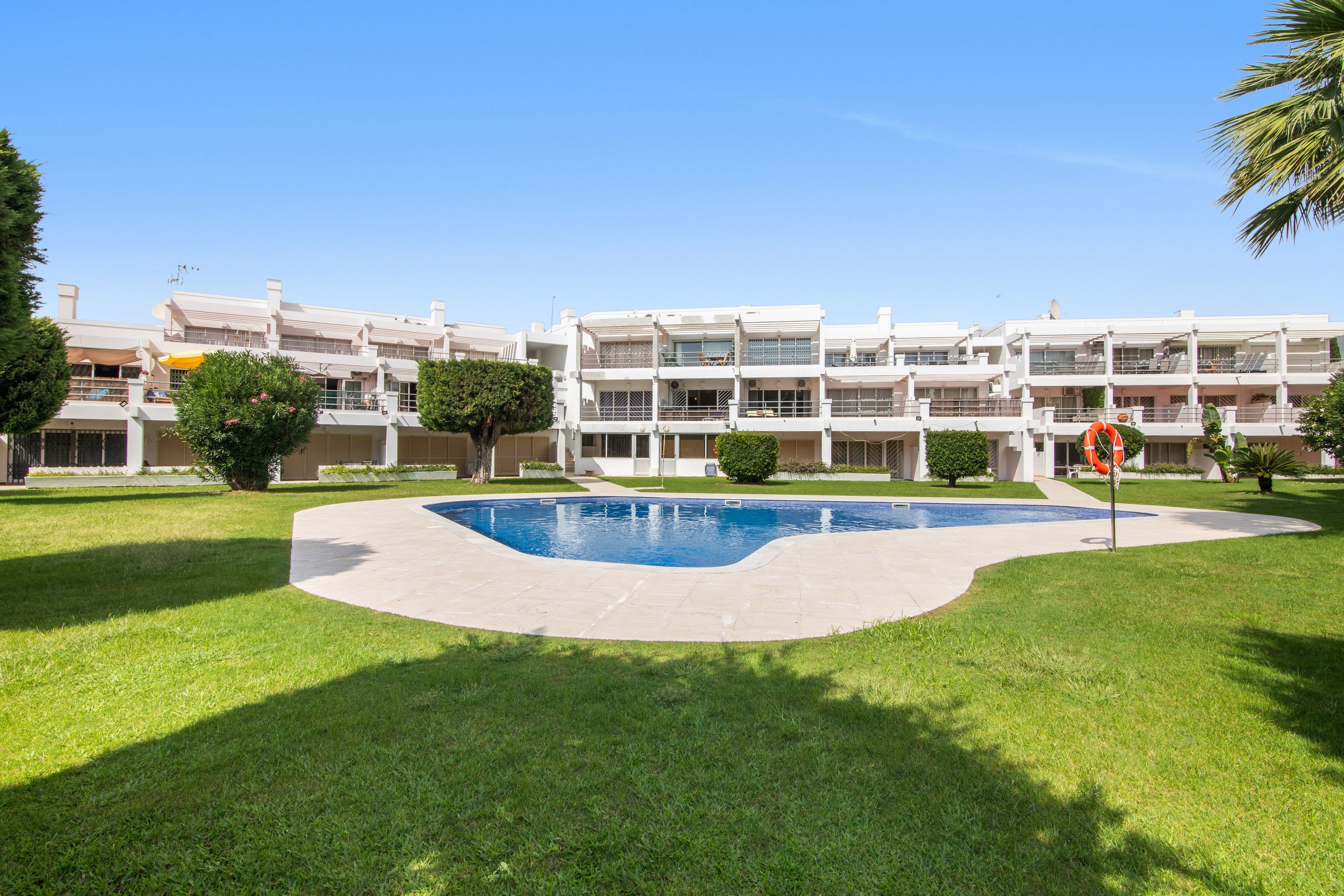 Un moderno edificio residencial con piscina y césped cuidado.