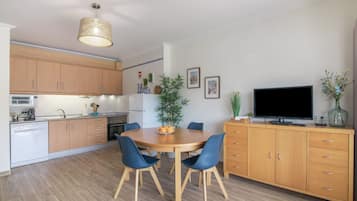Una cucina moderna con mobili in legno, un tavolo da pranzo con sedie, una televisione e una pianta.