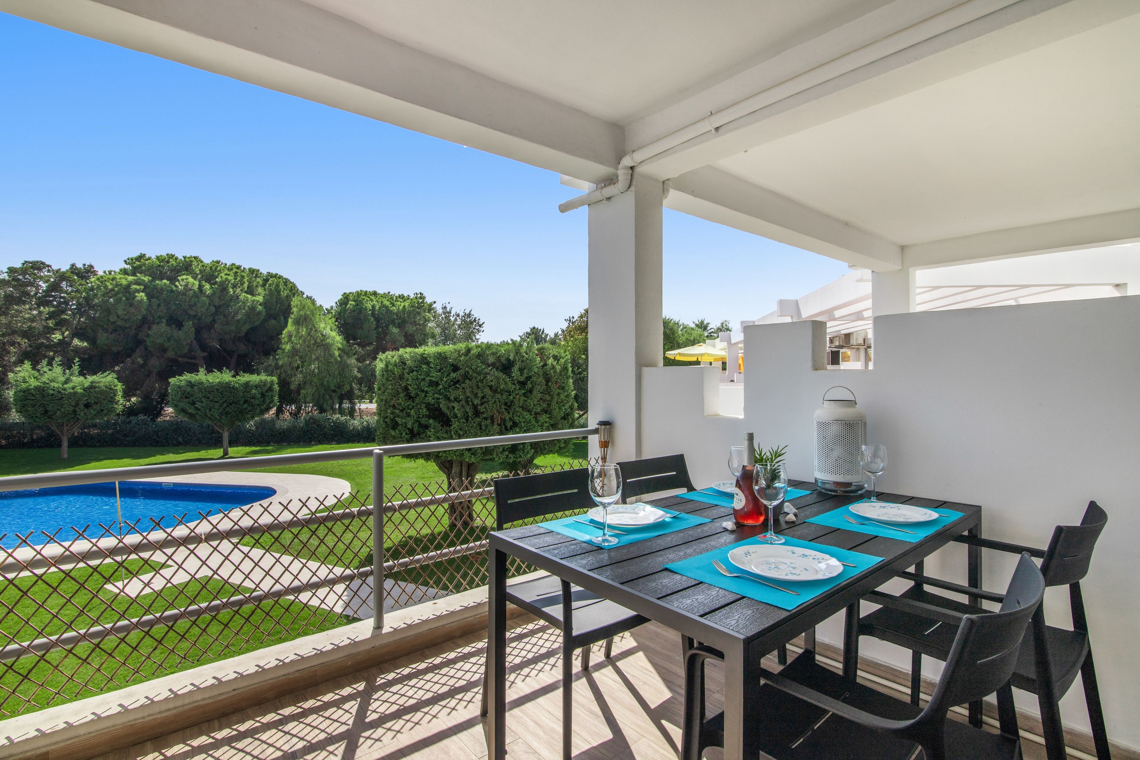 Una terrazza con un tavolo apparecchiato per mangiare, con vista su una piscina e un giardino curato.