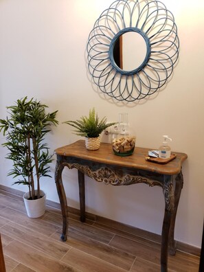 Een houten console tafel met een decoratieve spiegel en een glazen fles met pomp.