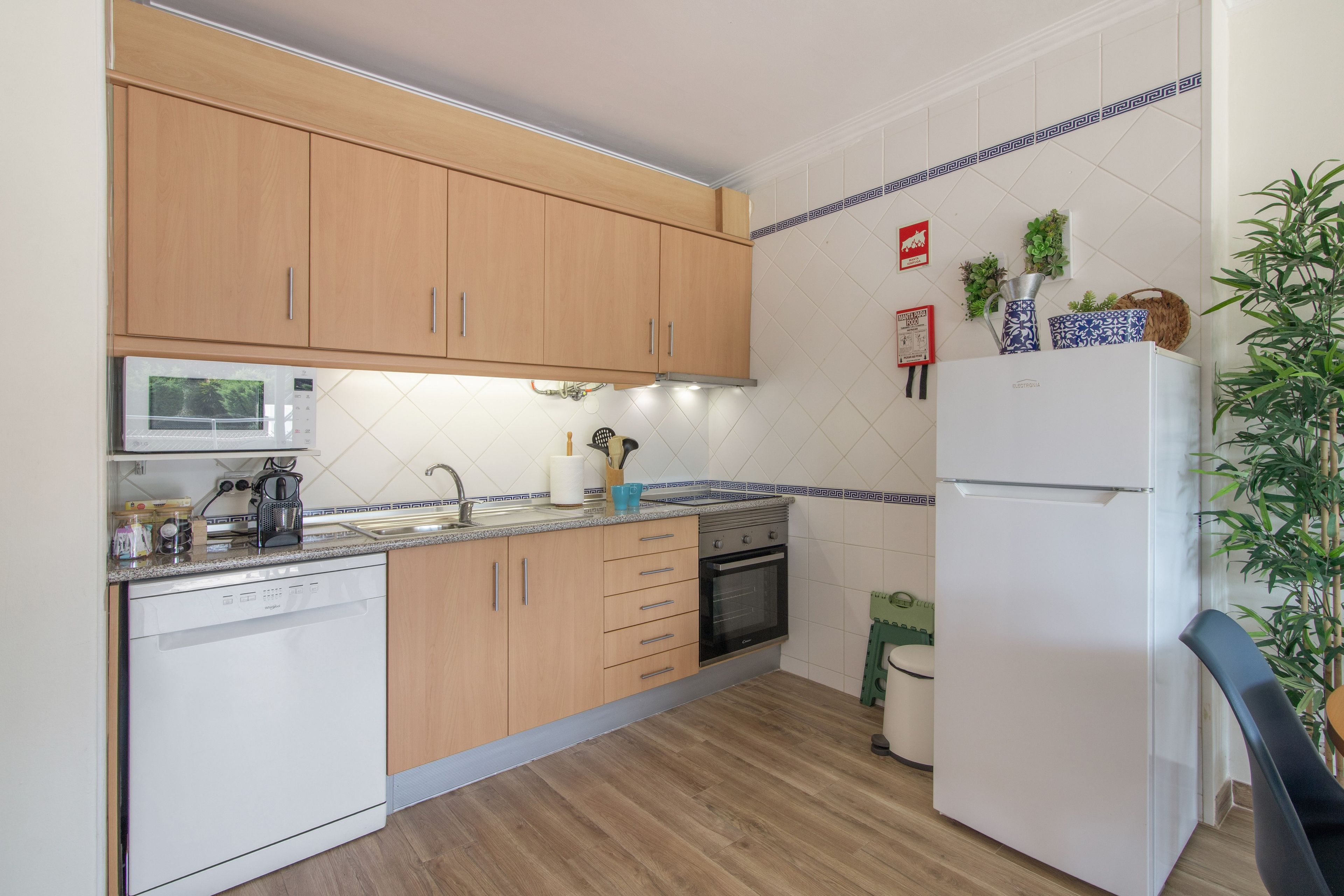 Een keuken met houten kastjes, een witte koelkast, een magnetron en een fornuis.