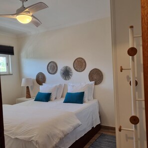 Een slaapkamer met een bed, een plafondventilator en wanddecoratie.