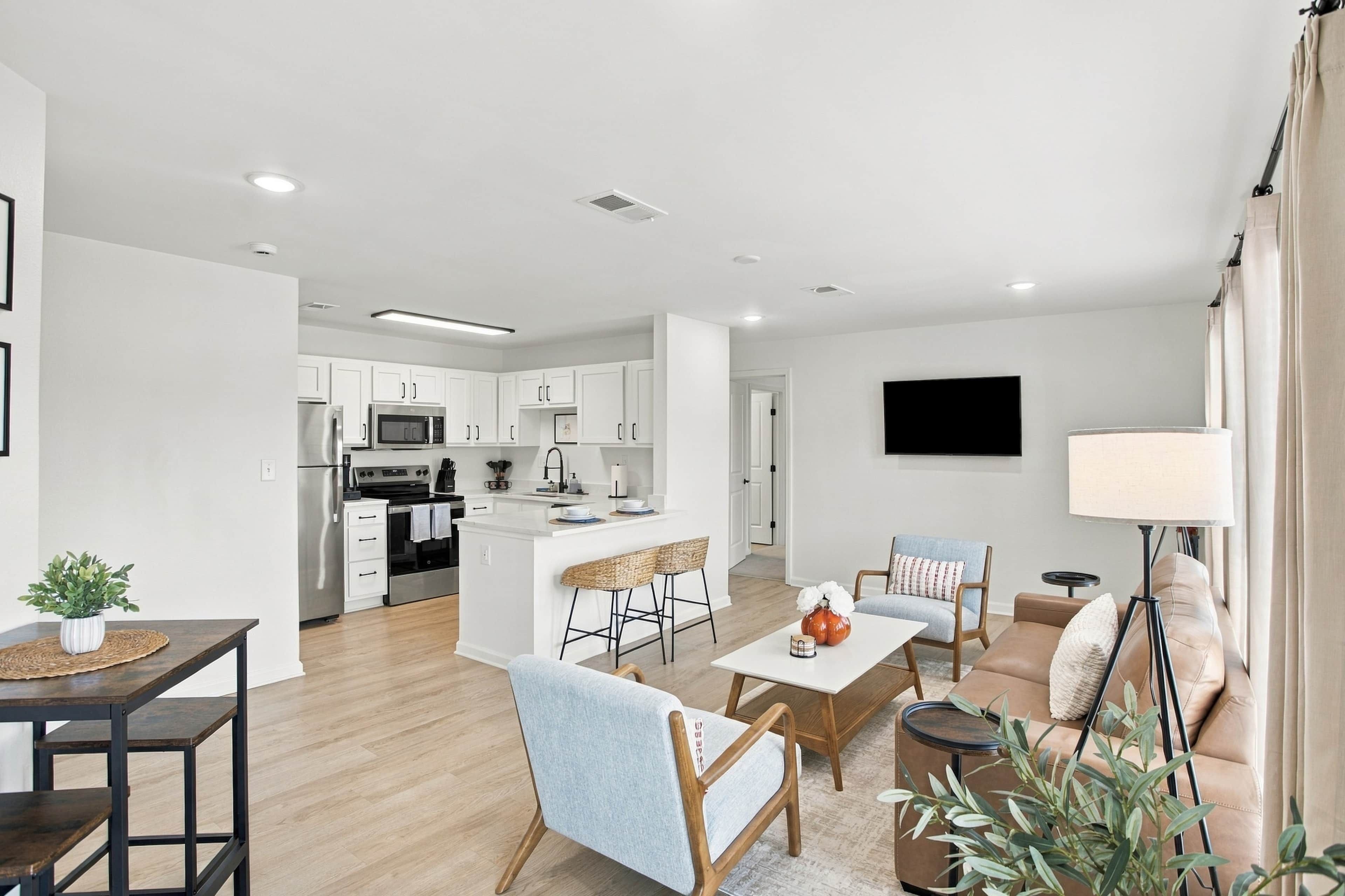 A modern apartment with a kitchen, dining area, and living room.